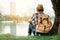 Asian man backpacking sitting under the tree on park background