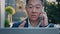 Asian man broker trader talking calling with phone looking at laptop screen in city Korean boss male investor