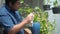 Asian man cleaning dust from green plant leaf by cloth at river front home. plant care concept.