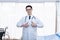 Asian man doctor standing in a patient and use his hands to make a great symbols