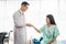 Asian man doctor talks to Asian woman patient in hospital office while  holding the patient hands doing basic medical examination