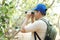 Asian man explorer holds binocular in forest to survey botanical plants and creatures wildlife.
