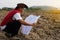 Asian man explorer wears hat, red vest shirt, holds map to explore land boundary.