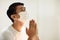 Asian man in face mask praying for coronavirus victim