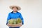 Asian man farmer wears hat, blue shirt, holds basket of durian fruits.