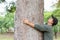 Asian man giving a hug on big mango tree. Take care the earth, Love tree and nature or environment concept