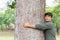 Asian man giving a hug on big mango tree. Take care the earth, Love tree and nature or environment concept