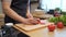 Asian man hands cutting tomato on chopping board. Close up shot of fresh vegetables on kitchen counter. Male is preparing food.