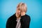 Asian man having headache, studio portrait. Korean stylish guy putting hands on head, isolated on blue background