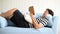 Asian man lying on blue sofa and reading book