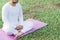 Asian man meditating on green grass in the park, calm and focused, health and yoga meditation concept, with copy space