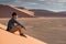 Asian man photographer sitting on sand dune