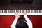 Asian man playing piano. Top view with red floor background.