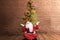 Asian man in Santa costume with open palm gesture sitting with Christmas tree