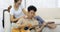 Asian man serenades sweetheart with guitar woman looks at boyfriend