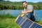 Asian man set solar cells panel and show thumbs up with look at camera during camping in national park near the lake