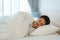 Asian man are sleeping and having good dreams in white blanket in the morning. Rest after work tiring in bedroom at home