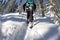 Asian man snowboarder freeride in snowshoes rises uphill in winter on snow