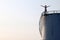 Asian man standing on the top of a large white Industrial tanks for petrol and oil