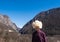 Asian man in traditional Caucasian sheepskin hat stands in background of Akhtsu Gorge in Caucasus Mountains. Observation deck on