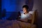 Asian man are typing online chat with a friend or girlfriend at night on a bed in a bedroom that is off the lights