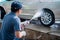 Asian man in uniform hands washes his car with a large head of water from a karcher and washing car with soap. Cleaning and