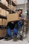 Asian man wheelchair user carrying parcel in postal warehouse