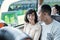 an asian man and woman chatting and laughing while sitting on the bus