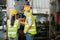 Asian man and woman engineering wear protection face mask and safety helmet working front machine in factory Industrial.