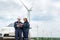 Asian man and woman Inspection engineers preparing and progress check with digital tablet of a wind turbine with safety in wind