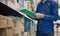 Asian manager man doing stocktaking of products management in cardboard box on shelves in warehouse using clipboard file and pen.