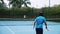 Asian mans dressed in tennis blue suits spending time on court,playing tennis on sunny day,holding a tennis racket