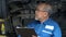 asian mechanic senior man holding clip board checking list to brake ,tyre, undercarriage of car in workshop at auto car repair