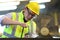 Asian mechanic worker in safety hard hat and reflective cloth is working with lathe machine in the factory