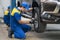 Asian Mechanician changing car wheel in auto repair shop