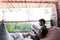 Asian men traveler wear black shirt while reading book and sitting on bean bad on resort balcony in relax mood vacation time/ trav
