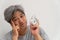 Asian middle-aged man is holding a white alarm clock and his face showed boredom and feeling bad, his problem is a sleep disorder.