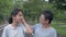 Asian middle aged mother wears eyeglasses caring her teen daughter while standing on the footpath in public park during summer.