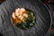 Asian miso soup ,soy sauce, greens and shrimps prawn. On a black stone background,  top view