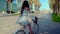 Asian model in a blue dress rides a white bicycle in a green park