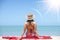 Asian model wear red swimsuit and straw hat sit on beach look view on hot day, Sun and UV rays.
