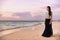 Asian model woman walking on beach at sunset relaxing on luxury Caribbean travel holiday wearing fashion maxi skirt outfit for