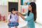 Asian mother Braiding her daughters hair sitting on chair, smiling single mom sister helping child girl with hairstyle at home