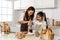 Asian mother and cute daughter, happy young mother teach cook together with small daughter doing bakery and learning to make cake