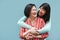 Asian mother and daughter hugging outdoors with blue background - Main focus on right face