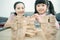 Asian mother and daughter playing wood block tower stacking game in cozy modern home. Ethnic babysitter engaging little girl in