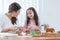 Asian mother and daughter preparing breakfast in kitchen, cute child have fun mixing salad, mom cutting apples, milk, bread,