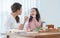 Asian mother and daughter preparing breakfast in kitchen, have fun mixing salad, mom peeling apples for cute child, milk, bread,