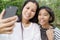 Asian mother and daughter selfie by smartphone together in the garden at home. A girl and women  smile when taking picture on