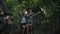 Asian mother and her teen daughter spread their arms happily with the wind blows while sitting on a huge rock in the forest.